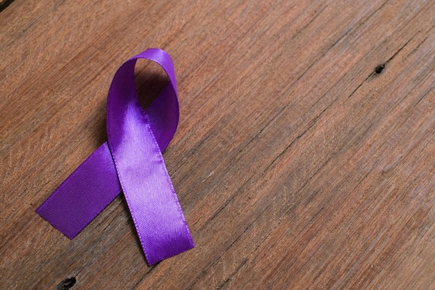 Cinta morada como símbolo del Día Mundial contra el Cáncer sobre fondo de color rosa