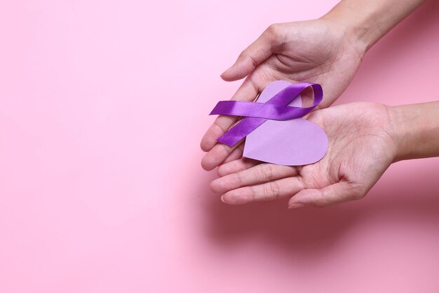 Cinta morada y forma de corazón en las palmas de las manos para apoyar el día mundial de la epilepsia y el día mundial del cáncer