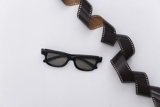 Cinta de película y gafas 3d sobre fondo blanco. Ã Â¡inema, industria del entretenimiento. Vista superior