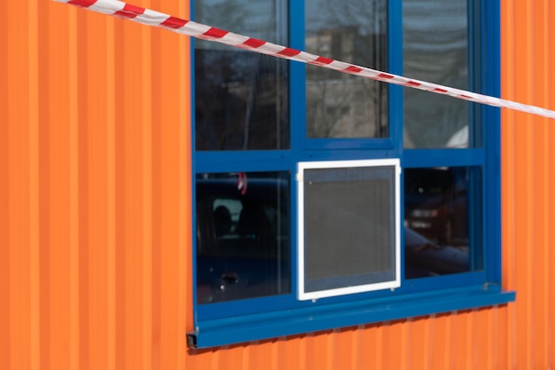 Cinta de precaución de advertencia roja y blanca contra el fondo de una ventana de mercado Robo de tienda Accidente en el territorio de estacionamiento pagado Advertencia de área insegura de peligro no ingrese Concepto de no entrada