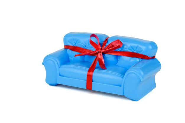 Cinta de regalo roja en sofá azul aislado en blanco. Una muestra de hermosos muebles para la casa. Minimalista.