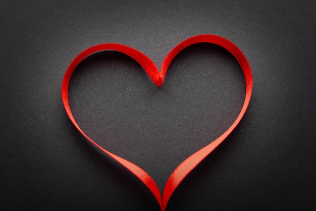 Cinta roja en forma de corazón sobre superficie gris