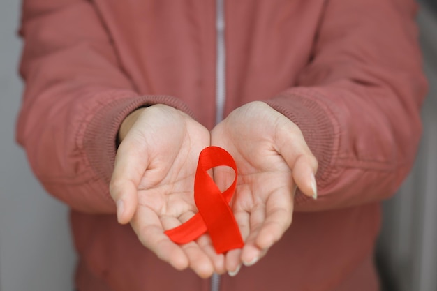 La cinta roja en la mano de la mujer es un símbolo de conciencia y apoyo para las personas que viven con el VIH / SIDA.