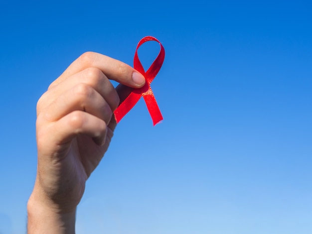 Cinta roja en la mano sobre un fondo de cielo azul