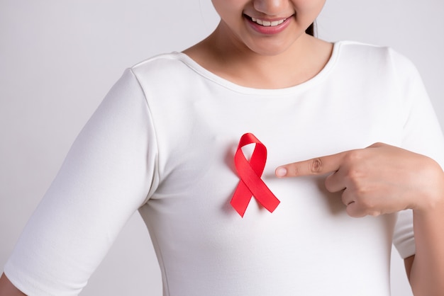 Cinta roja en el pecho de la mujer para apoyar el Día del SIDA. Concepto de salud.
