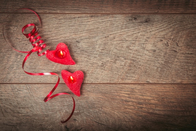 La cinta roja, velas en forma de corazón sobre una mesa de madera oscura. Antecedentes del día de San Valentín, estilo rústico, lugar de mesa con cinta roja. Mujer, concepto del día de la boda. Endecha plana, vista superior.