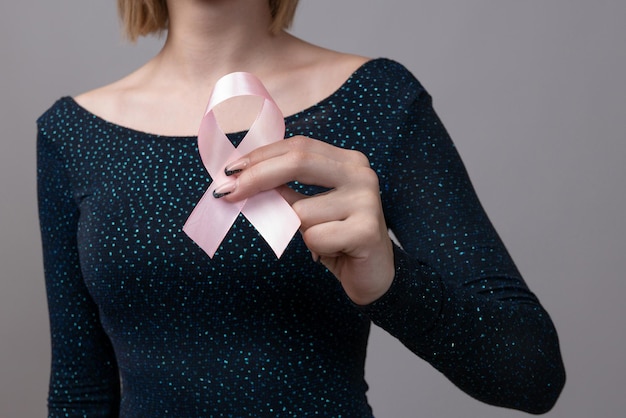 Cinta rosa para la concientización sobre el cáncer de mama en la mano de la mujer