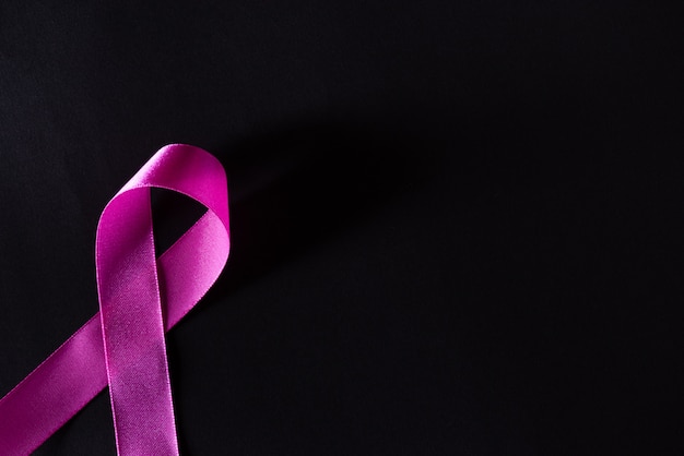 Cinta rosa sobre papel negro para apoyar la conciencia del cáncer de mama.