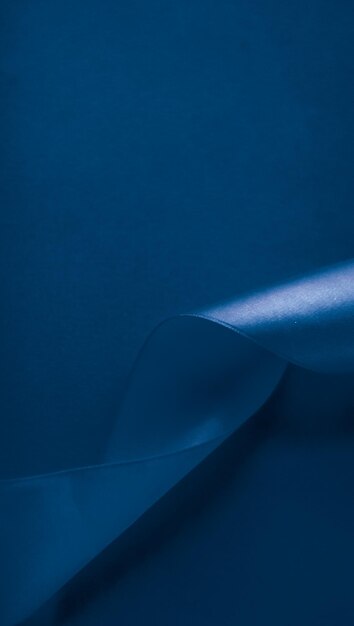 Cinta de seda abstracta sobre fondo azul real diseño de marca de lujo exclusivo para promoción de productos de venta de vacaciones y telón de fondo de tarjeta de invitación de arte glamour