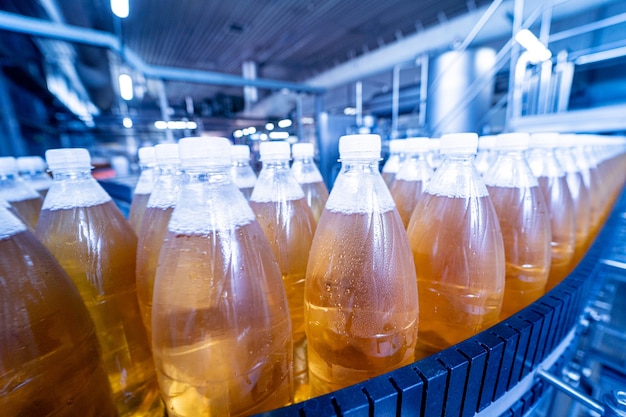 Cinta transportadora con botellas de jugo o agua en una moderna planta de bebidas