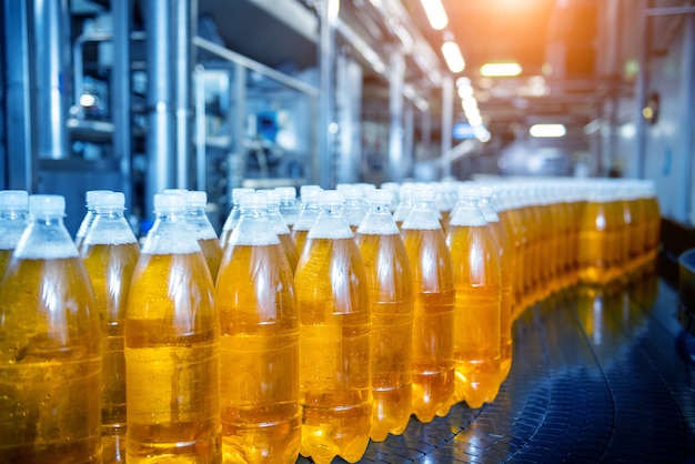 Cinta transportadora con botellas de jugo o agua en una moderna planta de bebidas