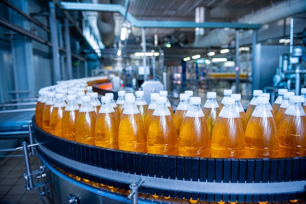 Cinta transportadora con botellas de jugo o agua en una moderna planta de bebidas