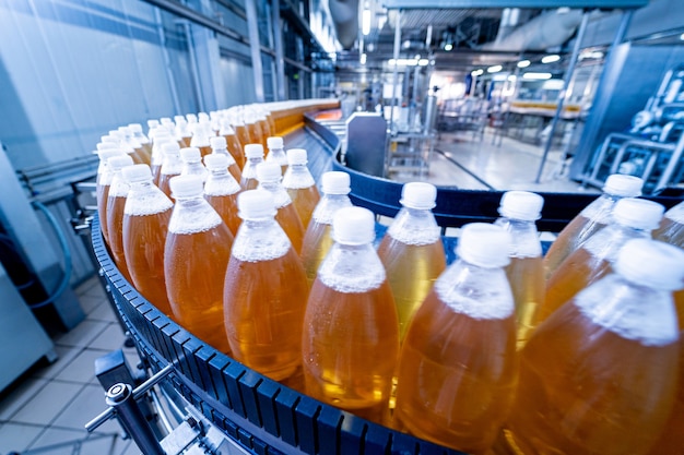 Foto cinta transportadora con botellas de jugo o agua en una moderna planta de bebidas