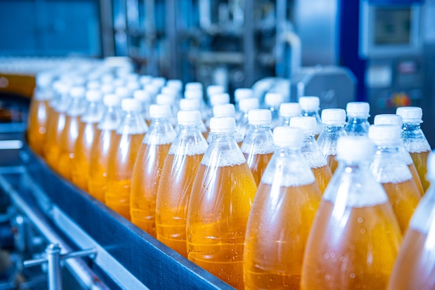 Cinta transportadora con botellas de jugo o agua en una moderna planta de bebidas