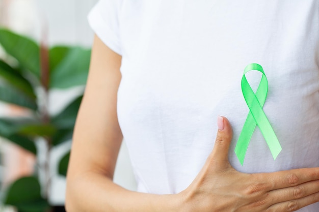 Cinta verde en la mano como símbolo de conciencia sobre el cáncer de linfoma