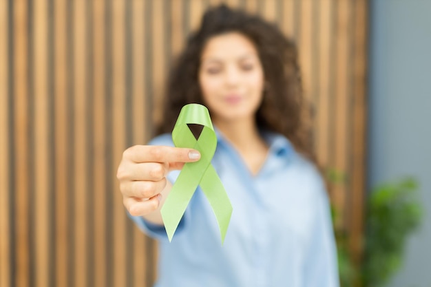 Foto cinta verde en la mano como símbolo de conciencia sobre el cáncer de linfoma