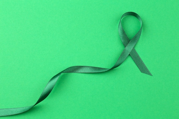 Foto cinta verde sobre fondo de color enfermedades mitocondriales y concepto de cáncer de riñón