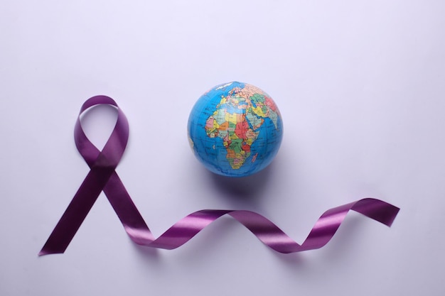 Cinta violeta púrpura y un globo terráqueo para el día mundial del cáncer