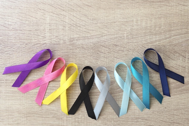 Cintas multicolores sobre fondo de madera Concienciación sobre el cáncer Día mundial del cáncer