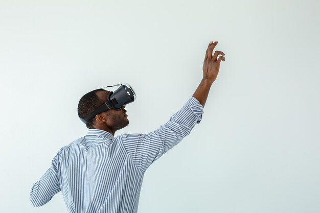 Cintura para arriba del agradable hombre afroamericano usando una placa mientras prueba gafas VR