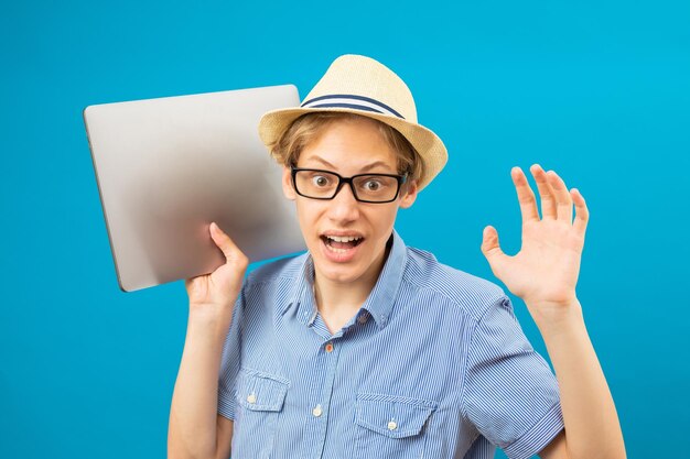 Cintura para arriba feliz vista de retrato del divertido hombre de negocios adolescente sosteniendo la computadora portátil en las manos