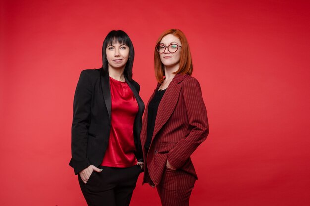 Cintura para arriba de hermosas mujeres empresarias de pie y posando a la cámara aislada sobre fondo negro