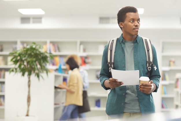 Cintura para arriba retrato de estudiante afroamericano sosteniendo la taza de café