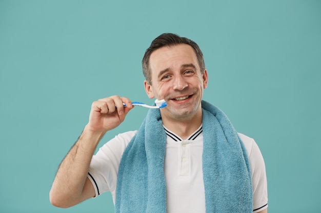 Cintura para arriba retrato de feliz hombre de mediana edad sosteniendo cepillo de dientes