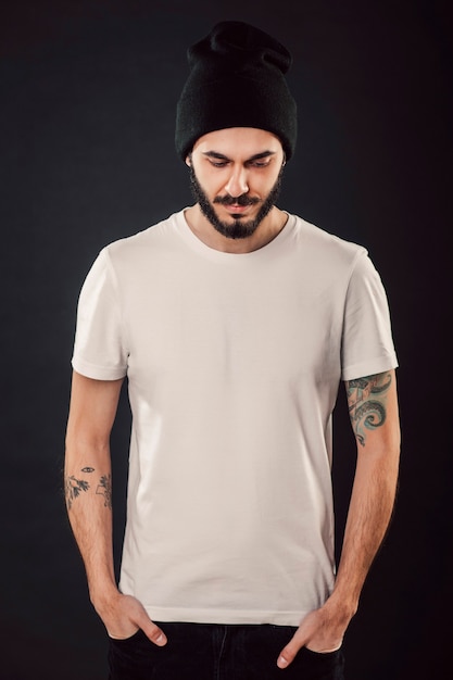 Cintura para arriba retrato de hombre atractivo elegante serio con barba espesa se ve con confianza, vestido con camiseta blanca informal