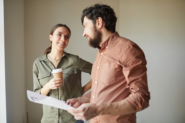 Cintura para arriba retrato de pareja feliz mirando planos de color mientras redecora la casa, espacio de copia