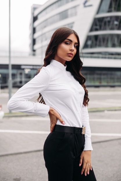 Cintura de jovem elegante, languidamente olhando para a câmera em pé na rua em roupas clássicas. Moda feminina