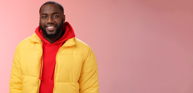 Cintura feliz carismático apuesto chico barbudo en chaqueta amarilla con capucha roja sonriendo alegremente blanco