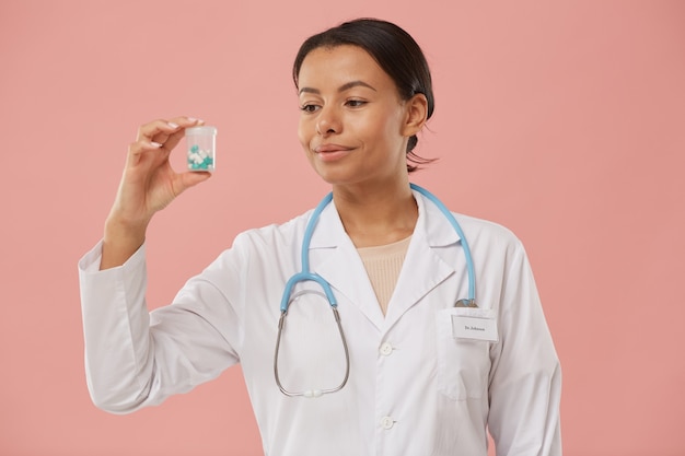 Cintura para cima, retrato da linda médica segurando o frasco de comprimidos