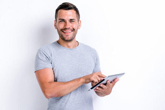 Cintura para cima retrato de homem barbudo sorridente segurando um tablet e apontando para a tela com um sorriso largo. Conceito de tecnologias e pessoas