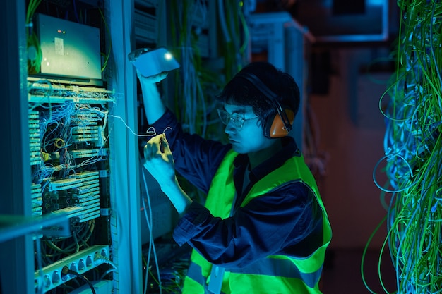 Cintura para cima retrato de um jovem técnico de rede consertando cabos na sala do servidor e configurando a conexão com a Internet, copie o espaço