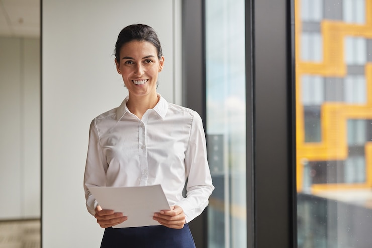 Foto cintura para cima retrato de uma empresária sorridente ao lado da janela no escritório,