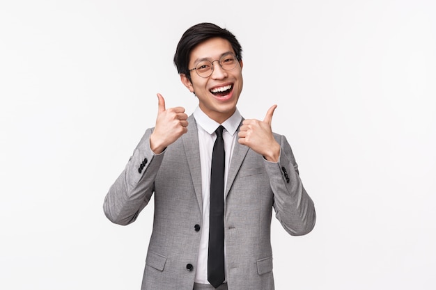 Cintura-se retrato de otimista, feliz e confiante jovem asiático empresário bonito terno cinza
