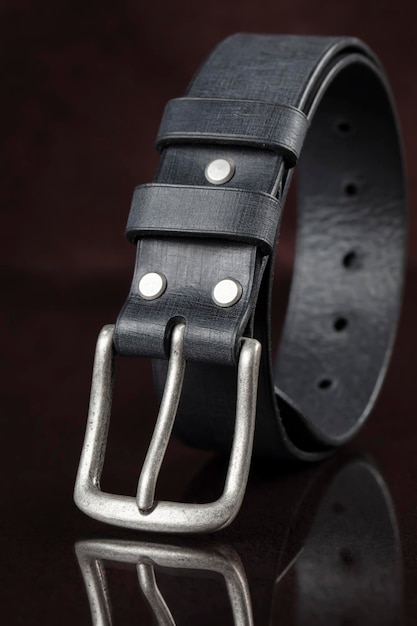 Cinturón de cuero negro sobre un fondo oscuro Productos de cuero
