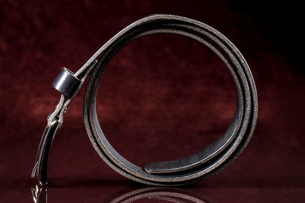 Cinturón de cuero negro sobre un fondo oscuro Productos de cuero