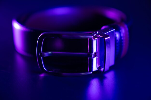 Cinturón de cuero negro sobre una mesa negra en la oscuridad con luz de color rgb. tienda de accesorios para hombres