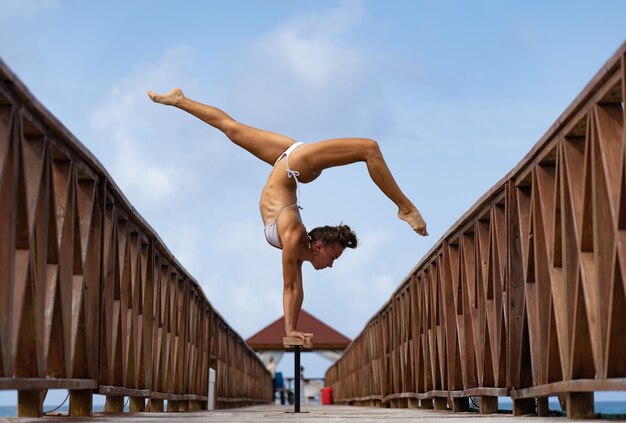 Circo feminino flexível fazendo parada de mãos de cabeça para baixo no cais