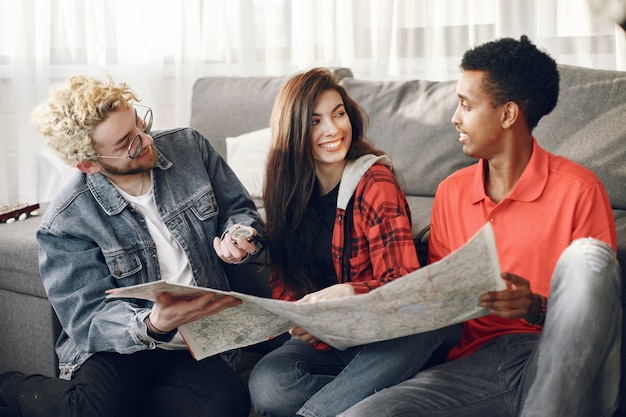 Círculo feliz de amigos planeando un viaje. Trotamundos inspeccionando un mapa estando en casa. Etnia europea e india.