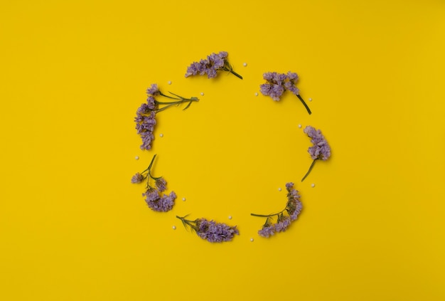 Círculo de flores de lavanda púrpura con perlas blancas sobre fondo amarillo