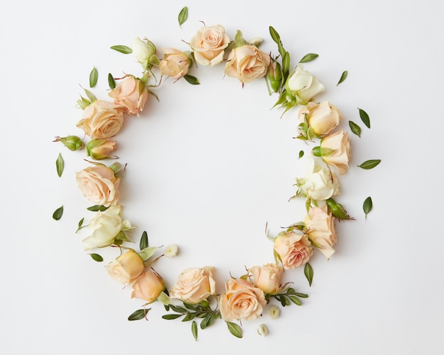 Círculo de hermosas rosas con pequeñas hojas verdes sobre fondo blanco.