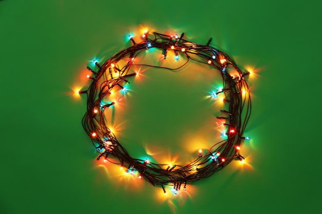 Círculo de luces de Navidad brillando sobre fondo verde