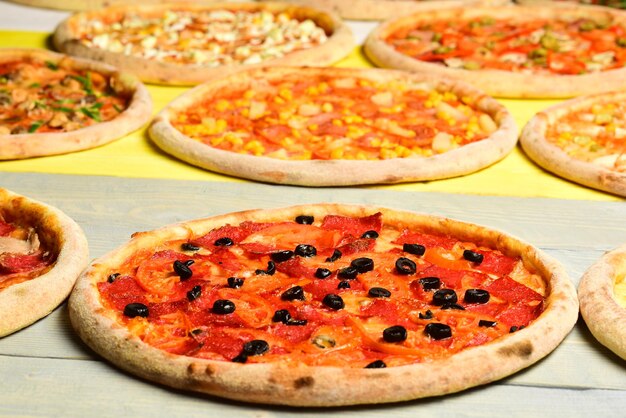 Círculos de pizza tomates pepperoni y aceitunas negras sobre fondo de madera