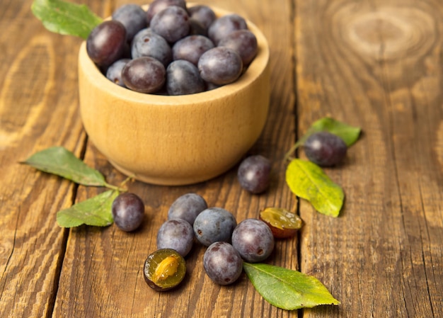 Ciruela azul en un recipiente sobre una mesa de madera Fondo de frutas con espacio de copia