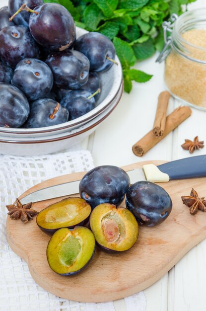 Ciruela orgánica cruda fresca con ingredientes de mermelada en una mesa de madera blanca.