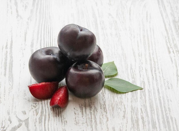 Ciruela roja fresca con hojas sobre un fondo de madera blanca Granja frutas saludables y ecológicas Estilo rústico