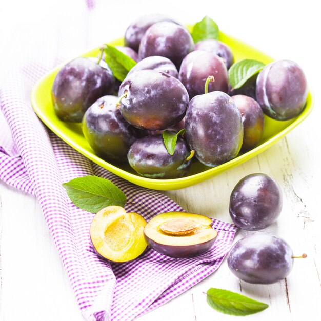 Ciruelas carnosas en un recipiente sobre la mesa